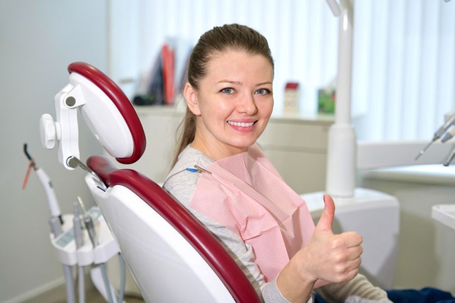 woman in a dentist chaie giving a thumbs up and smiling at the camera